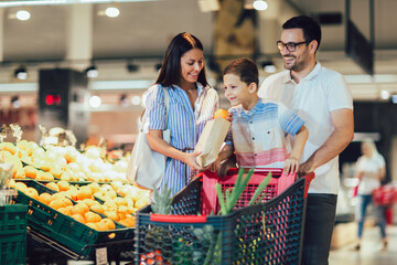Happy family buying fruit at grocery store or supermarket - shopping, food, sale, consumerism