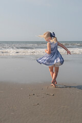 Young girl dances on the beach twirling her dress