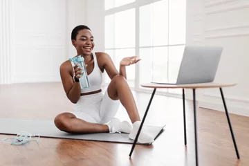 Gordijnen Young black woman woman exercising with online trainer using pc © Prostock-studio