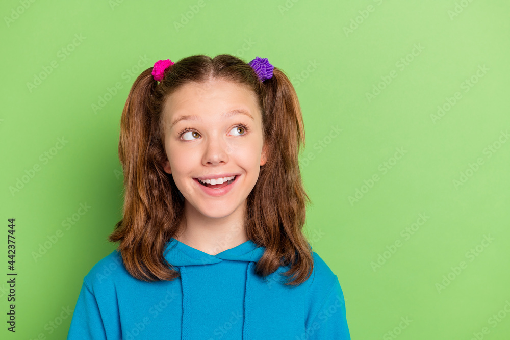 Sticker Photo of young happy small girl look empty space good mood charming face isolated on green color background