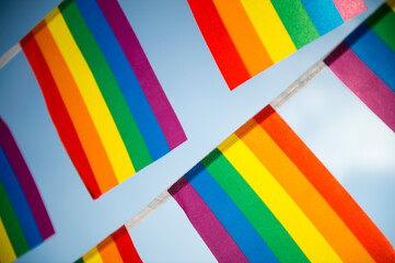 Close up of gay pride rainbow flag bunting fluttering against a bright blue sky