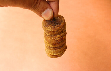 Hand holding a stack of dry figs or anjeer fruit
