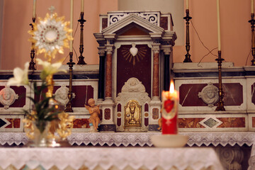 Tabernacle in the Church of the Sacred Heart of Jesus in Chiaravalle (Calabria, Italy), with blurred foreground (Altar, Ostensorium, Candle) during Eucharistic adoration
