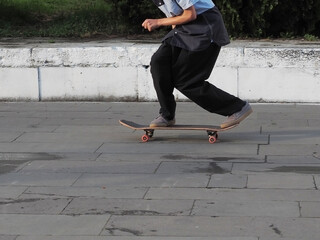 Teenager rides a skateboard squatting on a granite tiled area