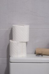 White toilet with some finished rolls of paper and others without touching.
