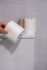White toilet with some finished rolls of paper and others without touching.