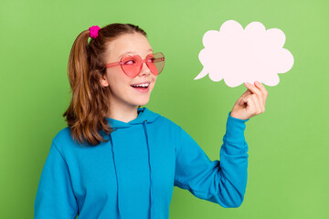 Photo of happy nice pretty little girl look clod speech smile talk wear sunglass heart isolated on green color background