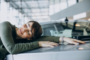 Young woman choosimng a car in a car showroom