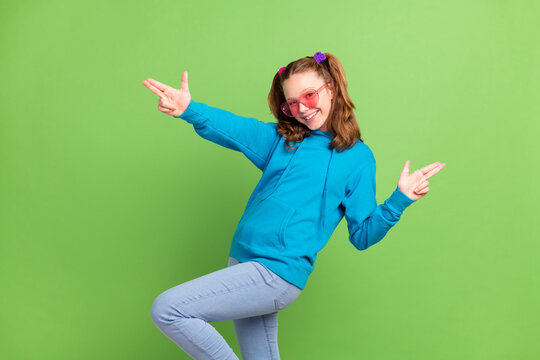 Photo of positive cheerful happy young girl fingers guns wear sunglass smile isolated on green color background