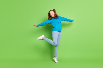 Fototapeta na wymiar Full body photo of charming cheerful small girl good mood enjoy raise leg isolated on green color background