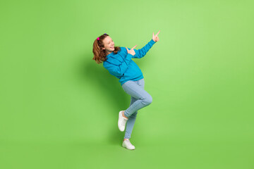 Fototapeta na wymiar Full body photo of cheerful young happy small girl point finger empty space advert isolated on green color background