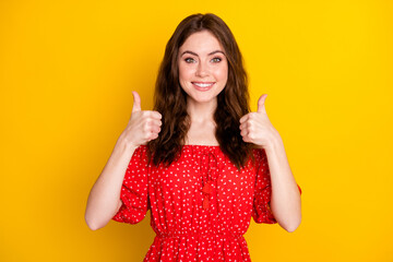 Photo portrait of curly girl in printed dress showing thumb-up sign gesture both hands isolated vibrant yellow color background