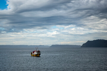 Small boat in the open sea on a day with many clouds