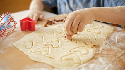 Closeup of little boy filling biscuit dough with raisins and nuts
