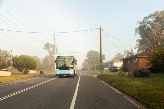 train replacement bus driving through misty street of town in morning