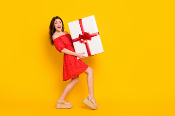 Full body profile portrait of astonished pretty lady hands hold large heavy giftbox isolated on yellow color background
