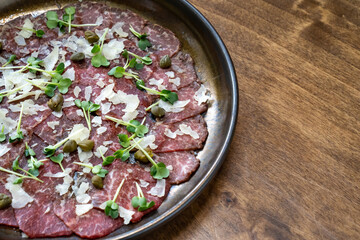 plate with dried meat with microgreen, capers and parmesan.