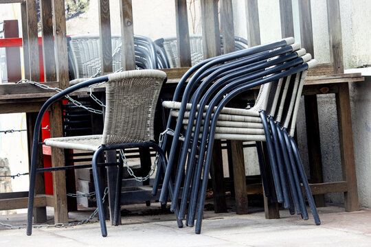 Stacked chairs near cafe tables standing on street
