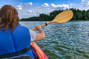 woman paddles a kayak across a lake