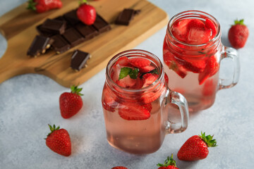 Strawberry drink in glass mug with berries and board with chocolate.