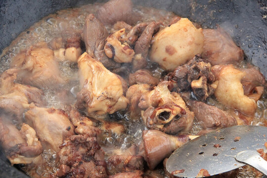 Large pieces of lamb meat with lamb fat dumba close-up fried in oil with bubbles in a black cauldron, cooking food