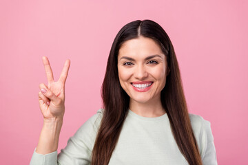 Photo of attractive mature happy nice woman smile show v-sign hello face isolated on pink color background