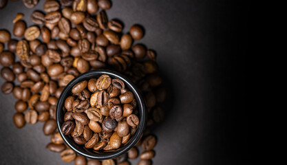 Ceramic cup with coffee beans on a blurred background from coffee beans scattered on a dark, top view, copy space.