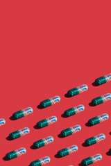 Vibrant colorful pattern of medicine pill capsules filled with sugar candy sprinkles on red background. Creative concept of overdose medicine usage and addiction to food supplement.