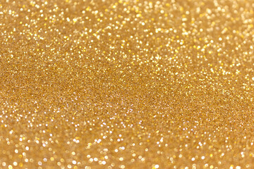 Golden glitter texture background. Glowing defocused backdrop.