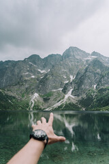 beautiful mountain view, man points to the top of the mountain, standing at the beginning of the lake