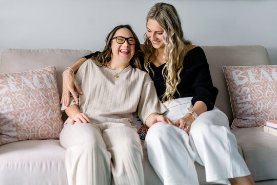 two women sitting on sofa, having a laugh.