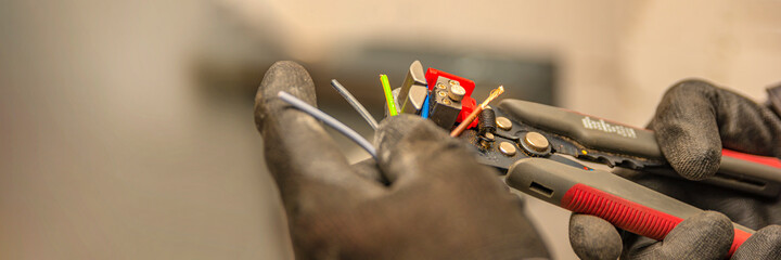 Wire strippers. The electrician cleans the protective insulation from the wire using a wire...