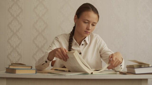 Woman student sits at desk, watch table of contents in old enciclopedia and look for right chapter, flipping through the book, Education concept, study at home library, do homework, preparing for exam