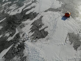 Winter fishing. lonely tent on ice fisherman . footprints in the snow. Holes. Aerial drone view from top down. Flying over. High quality photo