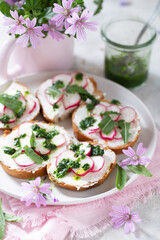 Crostini serviti in un vassoio bianco con crema di formaggio, pesto e ravanelli a rondelle