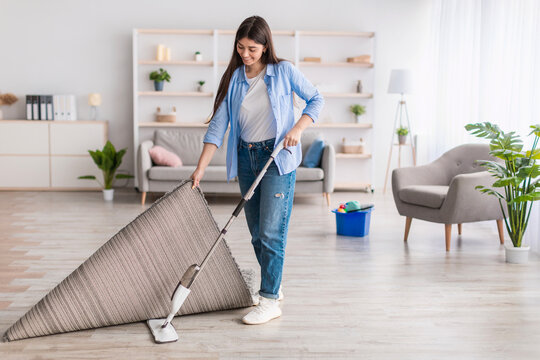 Portrait of woman cleaning floor in living room using mop
