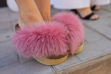 pink slop sandals with thick fur embellishment like pom poms.