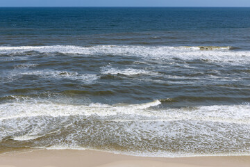 A drone shot of an empty beach with gentle waves