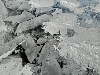 broken cracked Ice hummocks. footprints from fishermen on the snow. winter fishing. snow dunes. Dangerous. Nice pattern background. Aerial view from top down. drone view. Flying over.