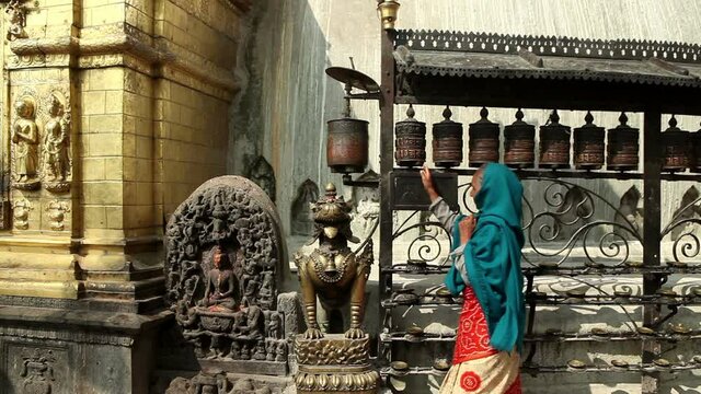 Nepalese woman spinning Tibetan prayer wheels.
