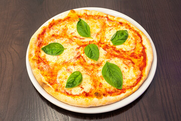 Typical Italian margarita pizza with lots of mozzarella cheese, tomato and basil leaves