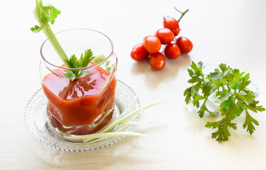 Tomato juice in the glass cup decorated with parsley and celery sticks.