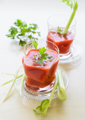 Tomato juice in the glass cup decorated with parsley and celery sticks.