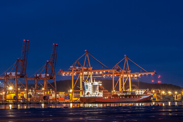 Fototapeta na wymiar Orange cranes unloading a cargo ship in the port of Gdynia.