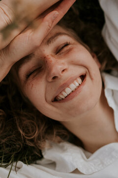 young happy woman with curls and freckles smiling