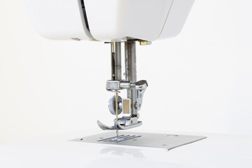 Detail of the foot of a sewing machine with a needle and its adjustments on a white background. Used for making clothes and shoes at home or in a factory.