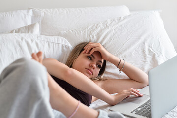 Young teenage girl laying on a bed using laptop computer