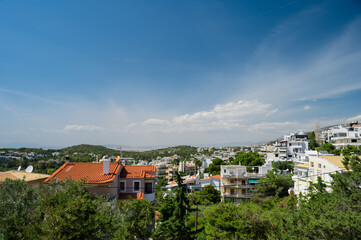 Naklejka premium Cityscape of Athens in Greece. Top view. Urban architecture and a lot of green trees. Hilly area. Sunne day.