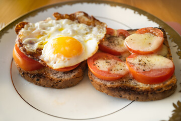 Fried tomatoes with an added egg and cheese on sliced brown toast.