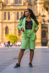 Lifestyle of a young girl of black African ethnicity with a beautiful green suit. Sightseeing in the city